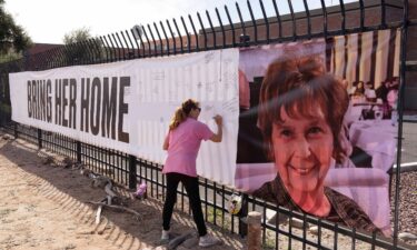 A woman signs a banner in honor of Nancy Guthrie
