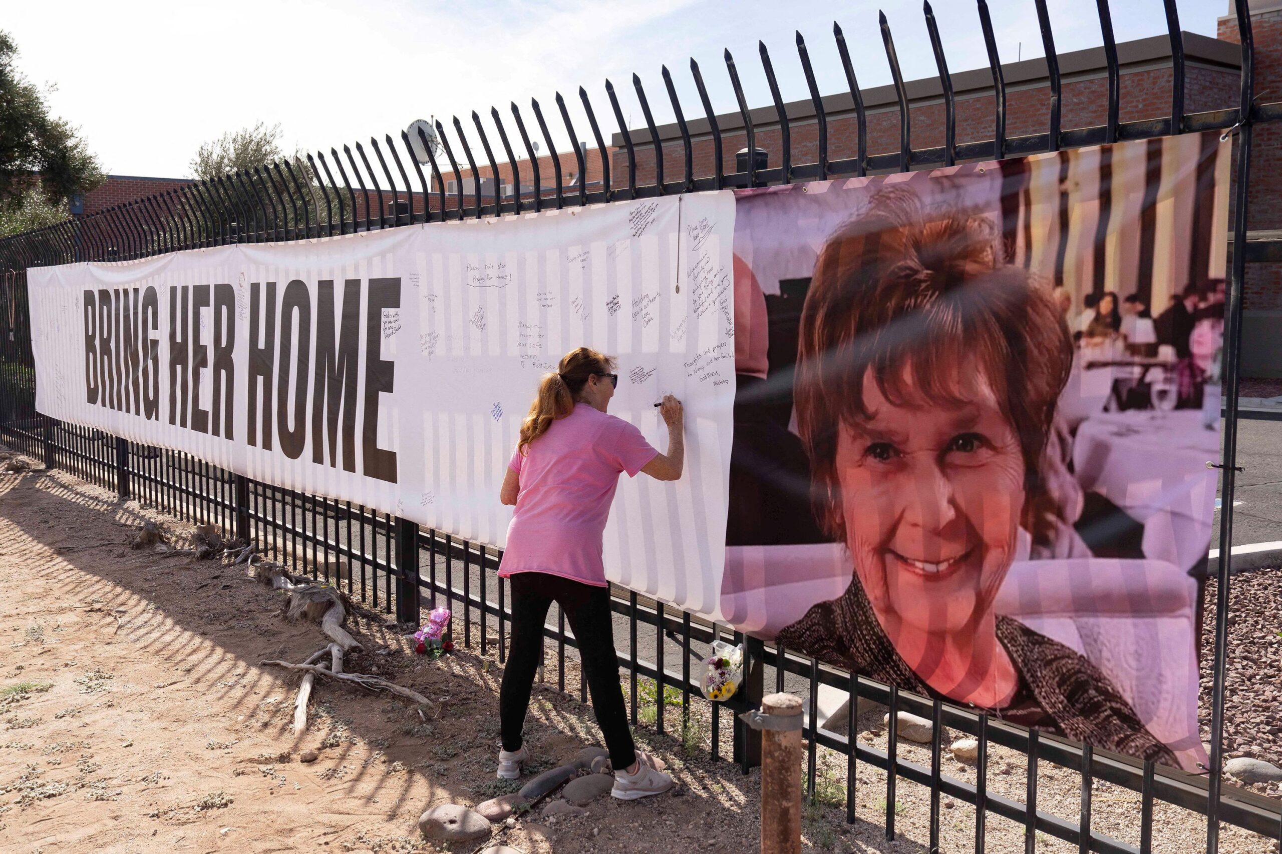 <i>Rebecca Noble/Reuters via CNN Newsource</i><br/>A woman signs a banner in honor of Nancy Guthrie