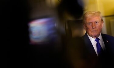 US President Donald Trump looks on as he speaks to reporters onboard Air Force One