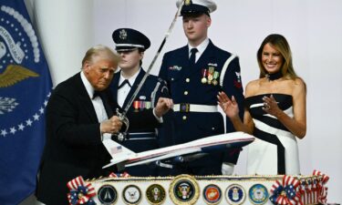 Donald Trump uses a saber to cut into a cake topped with a model of a new Air Force One design during the Commander-In-Chief inaugural ball on January 20.