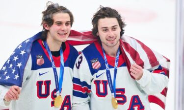 Jack Hughes and Quinn Hughes celebrate with the American flag and Olympic Gold medals