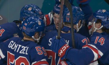 U.S. men's hockey players celebrate with Matt Boldy after he scores against Denmark in Olympic hockey.