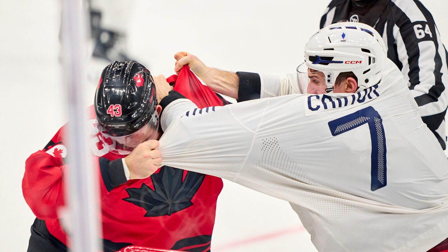 Canadian men's hockey player Tom Wilson fights with French player Pierre Crinon during a group stage game at the 2026 Milan Cortina Olympics.