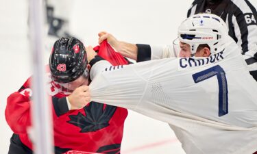 Canadian men's hockey player Tom Wilson fights with French player Pierre Crinon during a group stage game at the 2026 Milan Cortina Olympics.