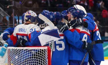 Slovakia's men's hockey team huddles near the goal on the ice with their arms on each other's shoulders after defeating Germany in the Olympic quarterfinal round.
