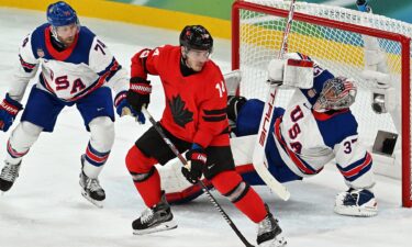 Connor Hellebuyck defends the goal against a Canadian player