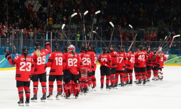The Canadian women's hockey team raises their sticks to the crowd while standing on the ice after the win over Germany in the Olympic semifinal round.