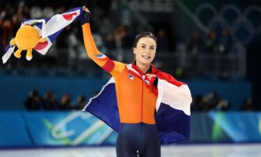 Femke Kok waves as she skates her victory lap with the Dutch flag