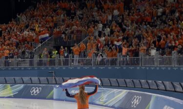 Speed skater holds Dutch flag and celebrates with cheering fans