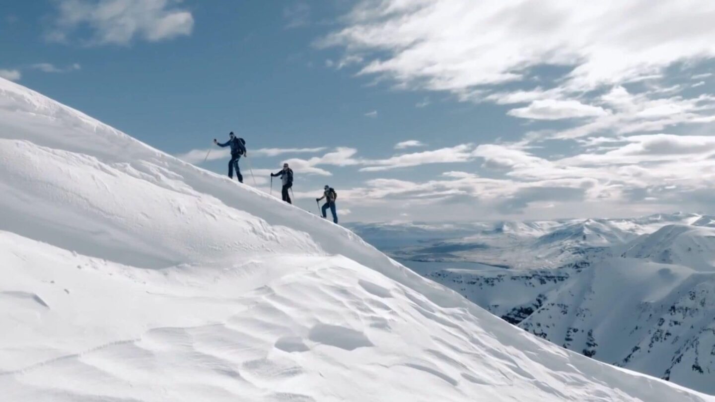 <i>NBC Olympics</i><br/>Two skiers ascend a mountain covered in snow