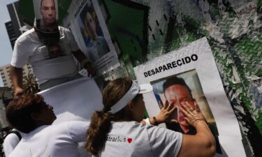 The mother of a missing person writes a message that reads "Mothers don't give up until they find them" on the esplanade of the Glorieta de los Desaparecidos (Roundabout of the Disappeared) during a mass offered for families on the International Day of the Victims of Enforced Disappearances