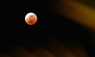 People gather near a telescope to watch the full blood moon in Caracas