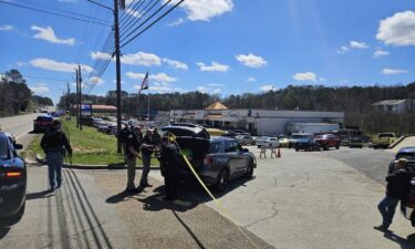 The shopping center where a Veterans Affairs employee was shot Tuesday is cordoned off by yellow tape and law enforcement vehicles.