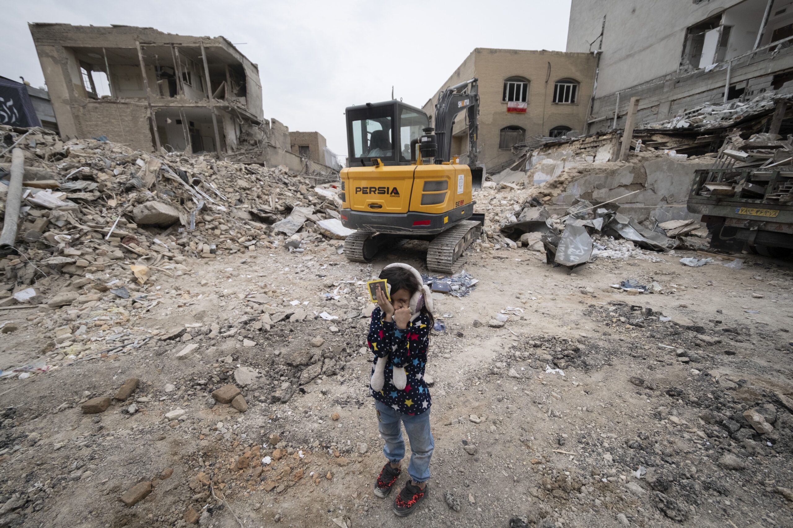 <i>Morteza Nikoubazl/NurPhoto/Getty Images via CNN Newsource</i><br/>A young Iranian girl closes her eyes near a loader working on the ruins of buildings destroyed during a military campaign in Tehran