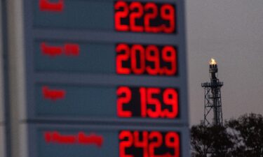A flare stack burns at the PCK Schwedt oil refinery beyond a sign for fuel prices at a gas station in Schwedt