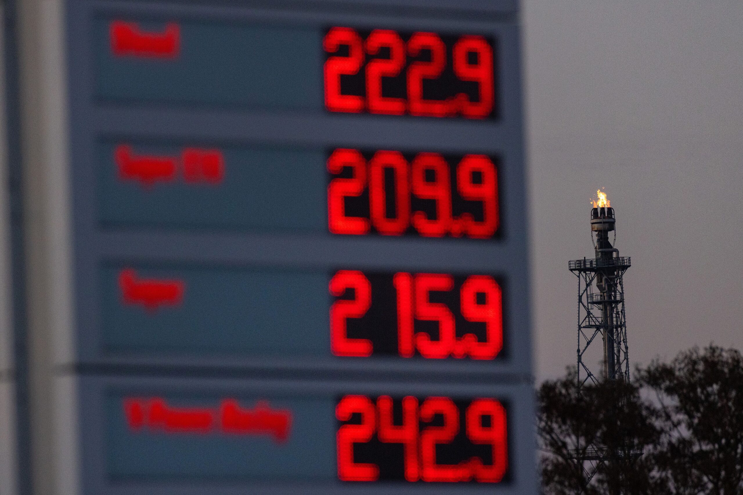 <i>Krisztian Bocsi/Bloomberg/Getty Images via CNN Newsource</i><br/>A flare stack burns at the PCK Schwedt oil refinery beyond a sign for fuel prices at a gas station in Schwedt