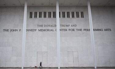 A person and a dog walk in front of the Kennedy Center in Washington
