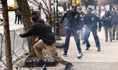 A man flees after throwing a homemade explosive device towards police during a protest in front of Gracie Mansion