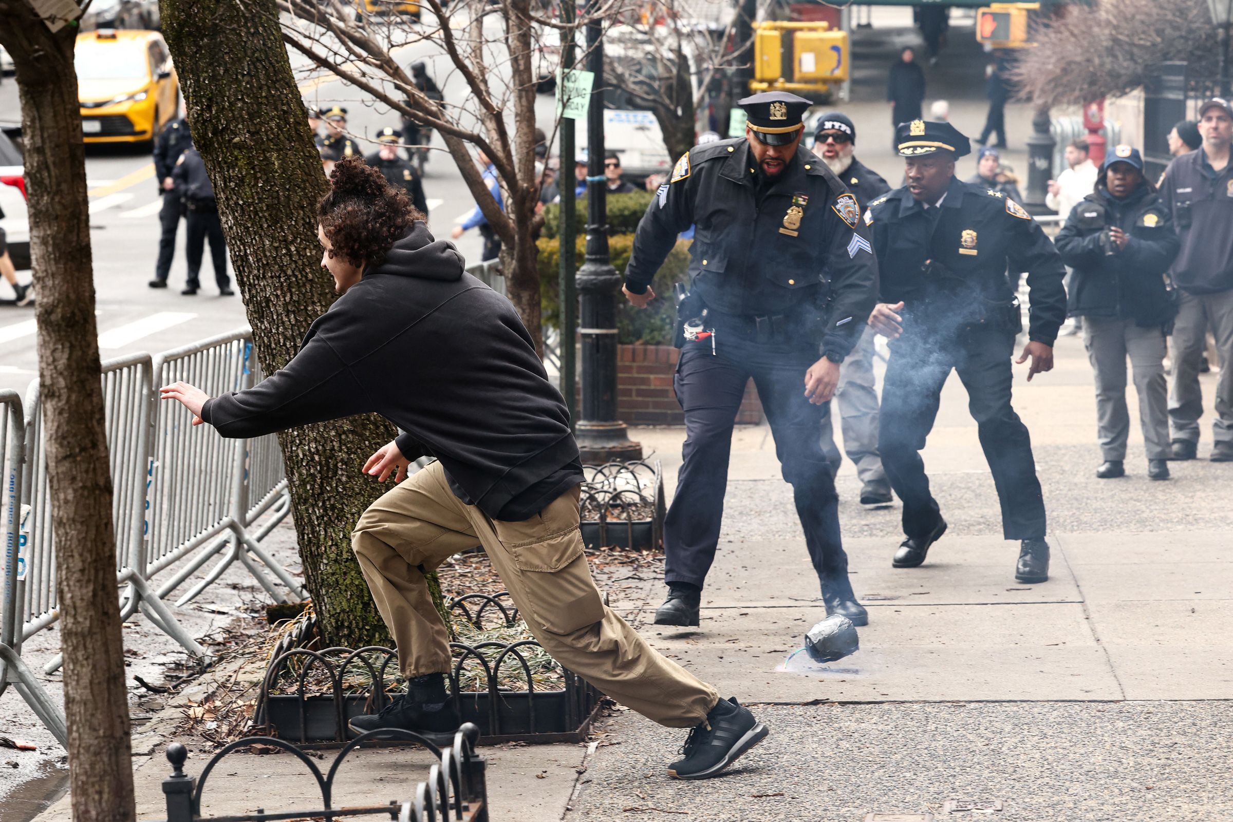 <i>Charly Triballeau/AFP/Getty Images via CNN Newsource</i><br/>A man flees after throwing a homemade explosive device towards police during a protest in front of Gracie Mansion