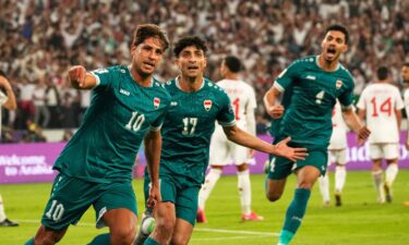 Iraq's Aymen Hussein raises his fist alongside head coach Graham Arnold as they celebrate getting past the UAE in November.