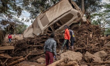 Young men inspect a car destroyed by flood waters in an area heavily affected by torrential rains