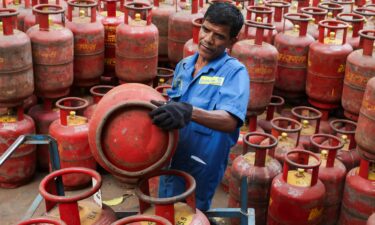 A man sits on an empty LPG cylinder as he waits outside a gas agency amid supply disruptions following the U.S.-Israeli conflict with Iran