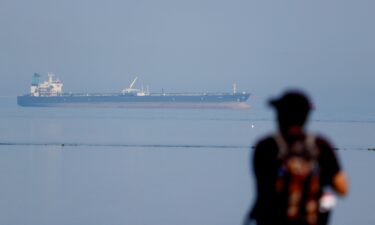 A tourist watches the MT Desert Kite oil tanker carrying Russian oil at Narara Marine National Park in the Arabian Sea