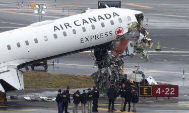 An aircraft rescue and firefighting vehicle lays on its side after colliding with an Air Canada Express regional jet landing at LaGuardia Airport