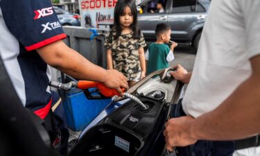A child walks along a hiking trail with oil storage tanks and facilities of CNOOC Ningbo Daxie Petrochemical Co.