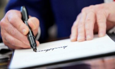 President Donald Trump writes his signature