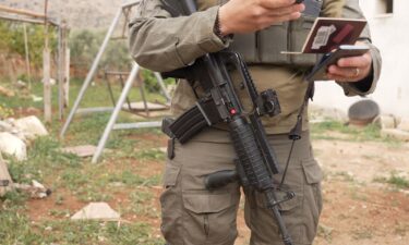 An israeli soldier's gun is seen as soldiers detain CNN crew members.