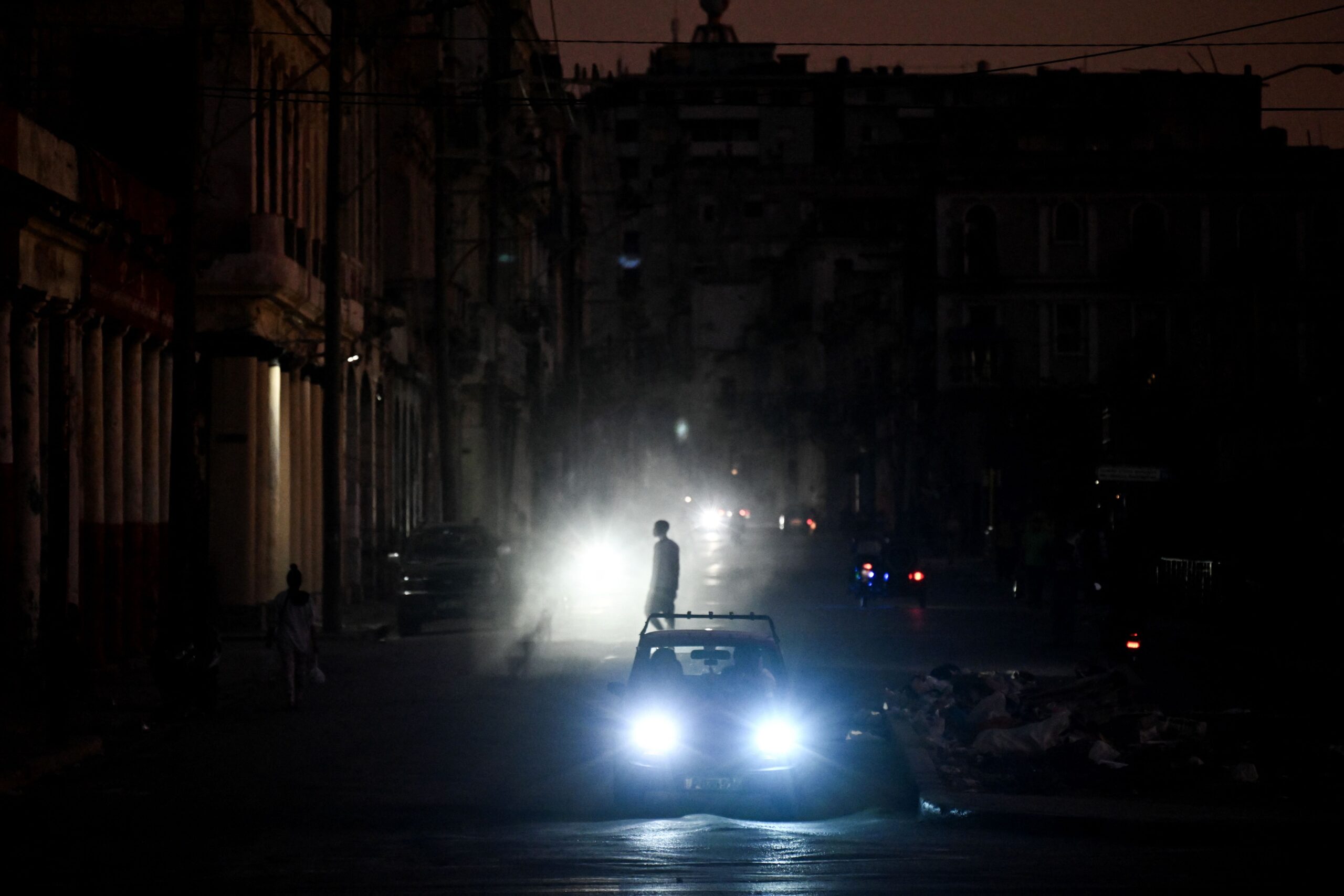 <i>Yamil Lage/AFP/Getty Images via CNN Newsource</i><br/>A man walks while cars cruise along a street during a blackout in Havana on March 16.
