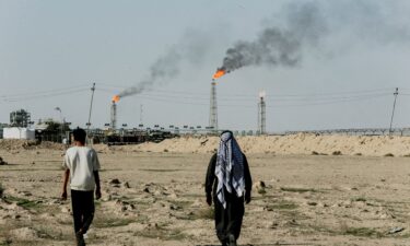 People walk on farmland near the Zubair oil field in Zubair Mishrif