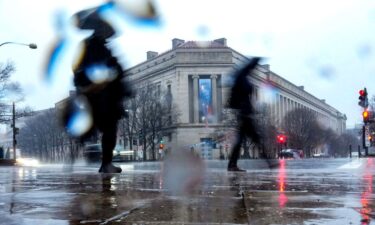 People walk in heavy rain near the Department of Justice building in Washington
