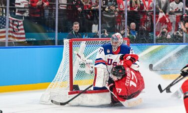 Connor Hellebuyck saves a shot attempt by Canada's Macklin Celebrini.