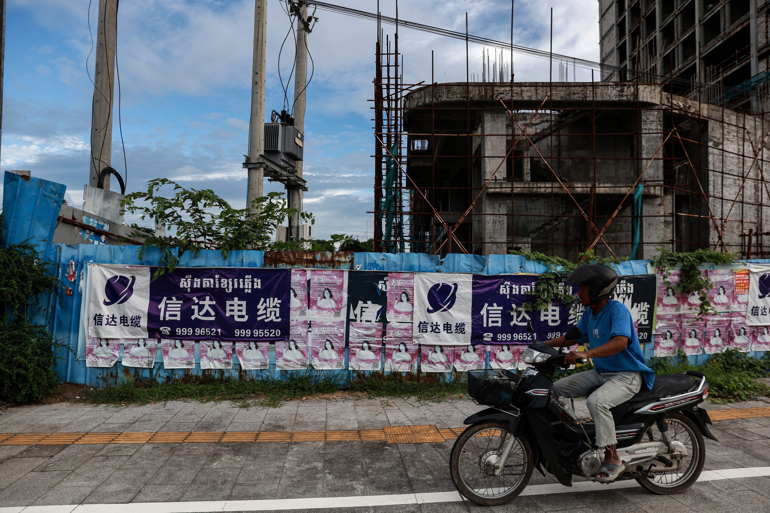 <i>Valeria Mongelli/Getty Images via CNN Newsource</i><br/>A motorbike rides past an unfinished building in Sihanoukville
