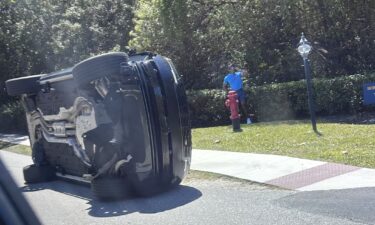 Golfer Tiger Woods stands by his overturned vehicle in Jupiter Island