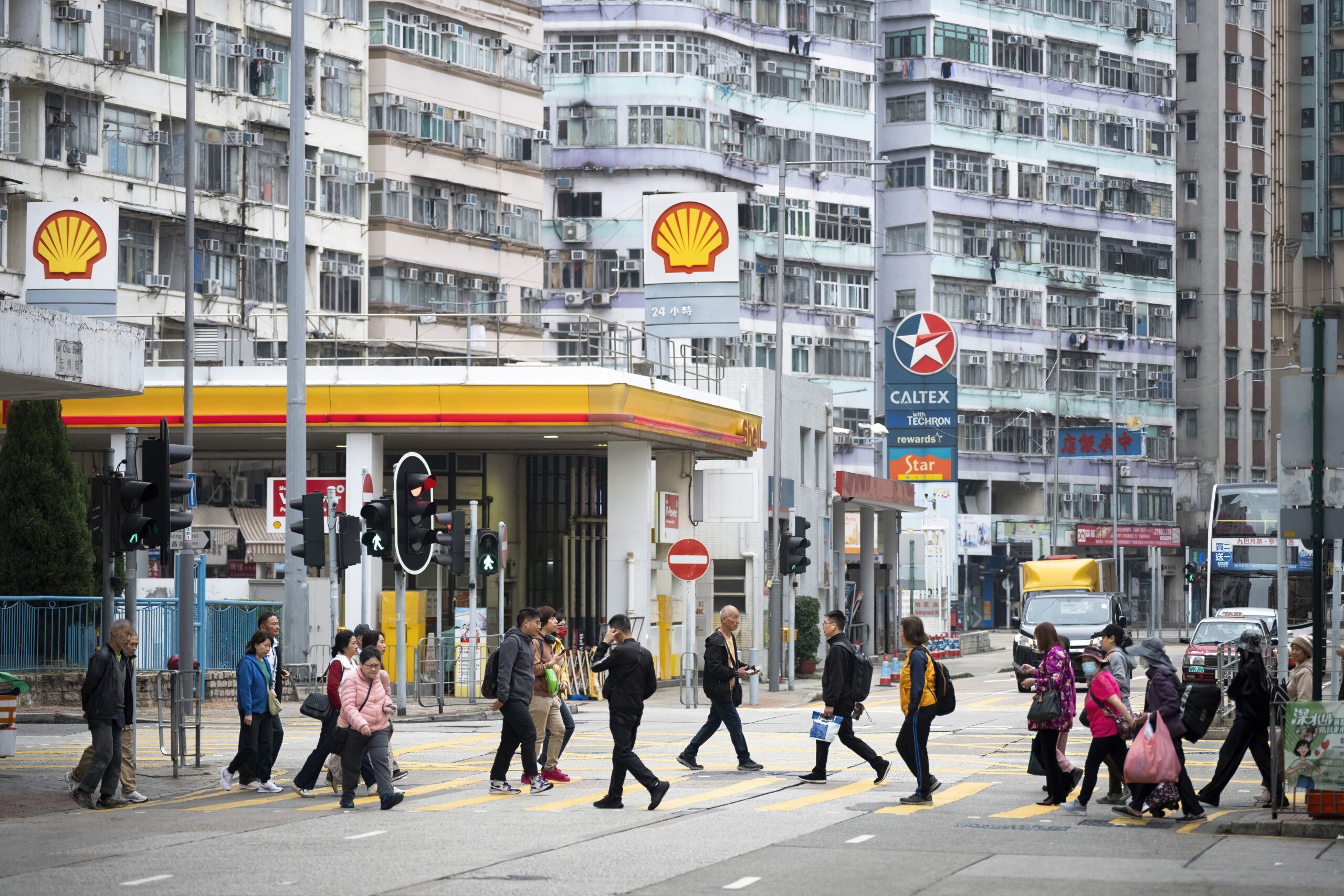 <i>Sebastian Ng/SOPA Images/LightRocket/Getty Images via CNN Newsource</i><br/>Pedestrians walk through a zebra crossing in front of the gas stations logos from the energy and petrochemical company