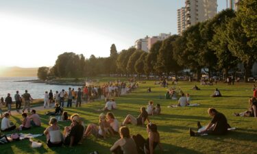 Crowds gather for a sunset at English Bay Beach in Vancouver in the Canadian province of British Columbia.
