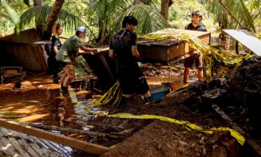 Volunteers carry debris from a home impacted by flooding in Haleiwa