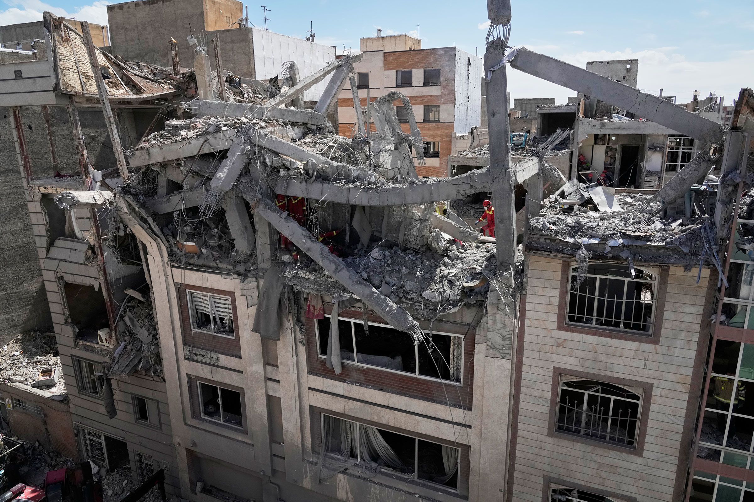 <i>Vahid Salemi/AP via CNN Newsource</i><br/>First responders inspect a residential building hit in an earlier US-Israeli strike in Tehran