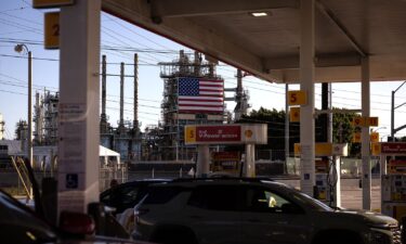 People put gas in their cars at a Shell gas station located in front of the ConocoPhillips Oil Refinery in Wilmington