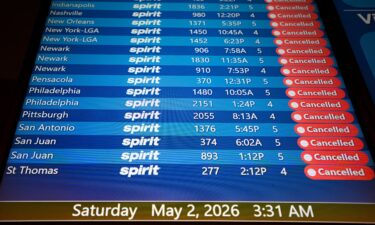 An employee sticks a Spirit Airlines operational update notice at Orlando International Airport on May 2