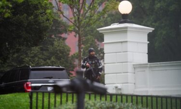 A US Secret Service agent stands guard holding his weapon after alleged gunshots were heard nearby