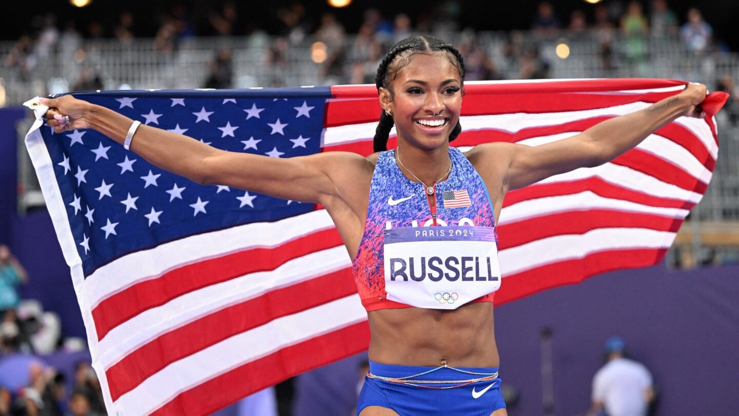 TOPSHOT - Gold medallist US' Masai Russell celebrates with the national flag after winning the women's 100m hurdles final of the athletics event at the Paris 2024 Olympic Games at Stade de France in Saint-Denis