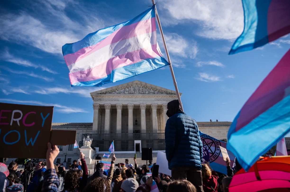 Protesters wave transgender pride flags outside the Supreme Court as it hears arguments over state laws barring transgender girls and women from playing on school athletic teams in January in Washington, DC.