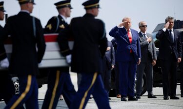 President Donald Trump salutes as transfer cases for fallen soldiers are carried at Dover Air Force Base in Delaware on July 22.