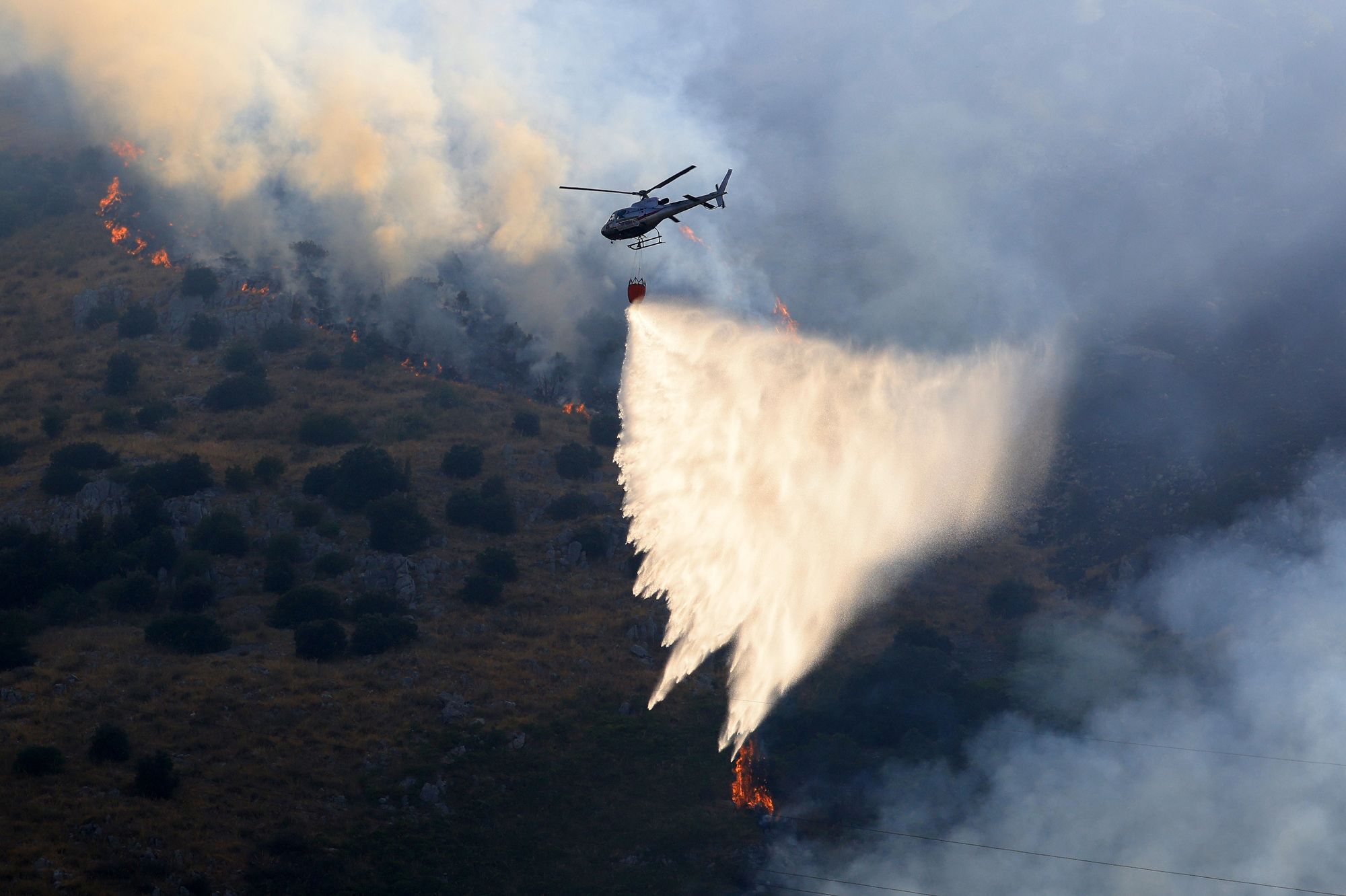<i>Alberto Lo Bianco/Anadolu/Getty Images via CNN Newsource</i><br/>Firefighting aircraft and helicopters try to bring a fire under control on the slopes of Mount Longa near Palermo