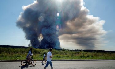 Local residents walk past the smoke of a fire at the Russian e-commerce firm Wildberries' logistics complexes in the town of Elektrostal outside Moscow on July 18.