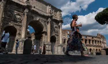 People walk by the Colosseum in Rome